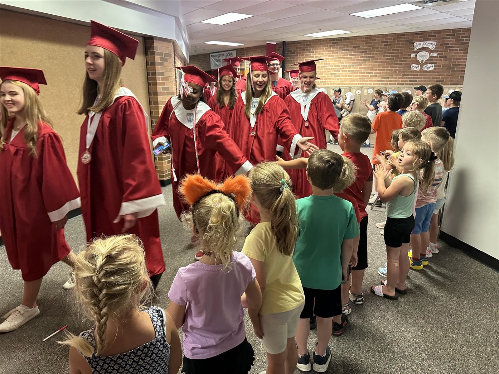  2023 graduates giving high-5s to elementary school students